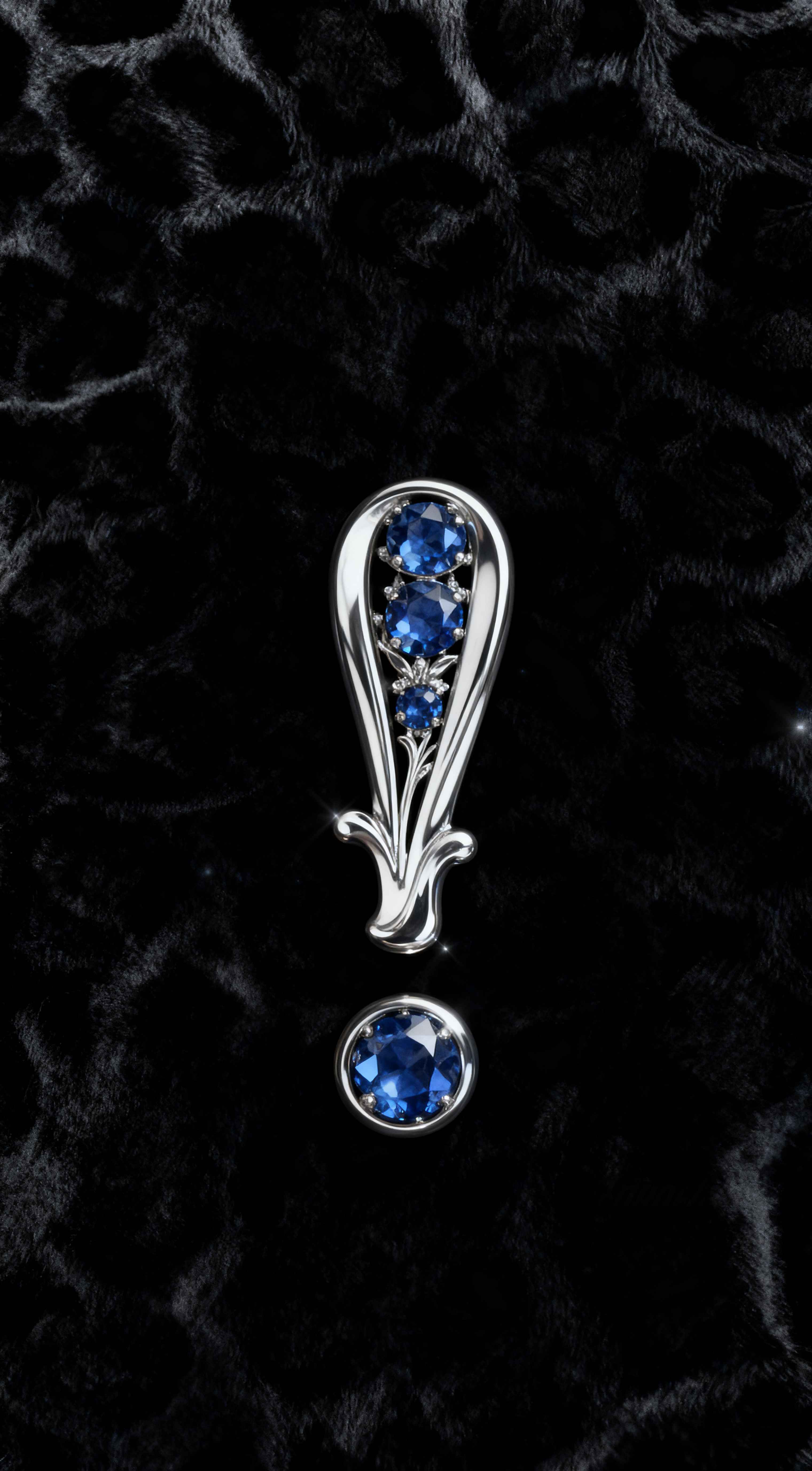 Silver exclamation mark jewelry with blue sapphires on a textured black fur background, high-end luxury aesthetic.