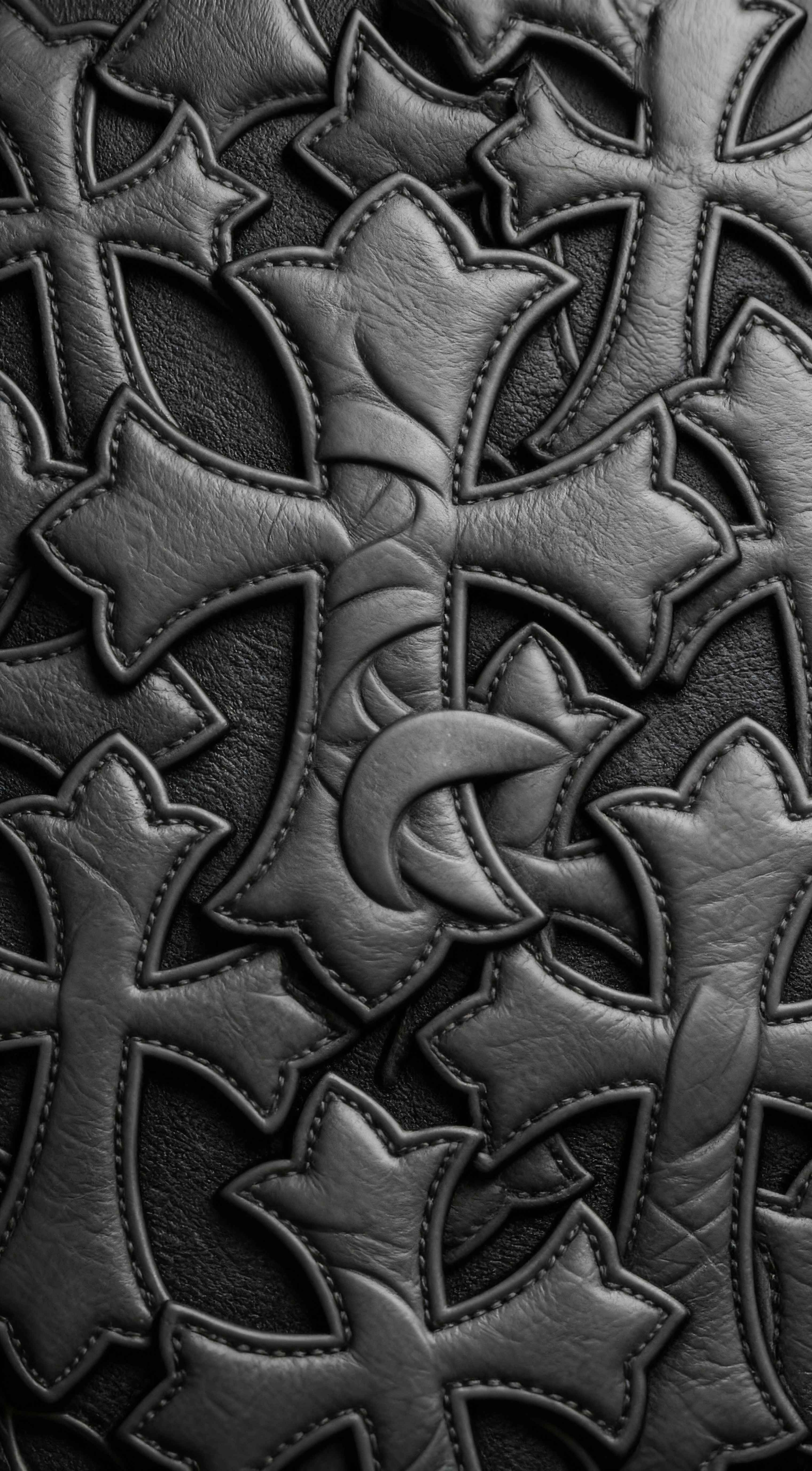 Detailed close-up of black leather crosses with visible stitching in a dark gothic aesthetic for mobile wallpaper.