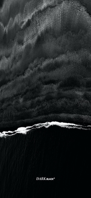 Vertical aerial shot of a black sand beach with white foam waves in high contrast black and white.