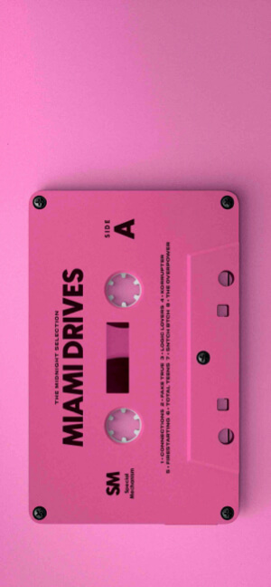 A top-down vertical shot of a vibrant pink cassette tape labeled 'Miami Drives' against a matching pink background.