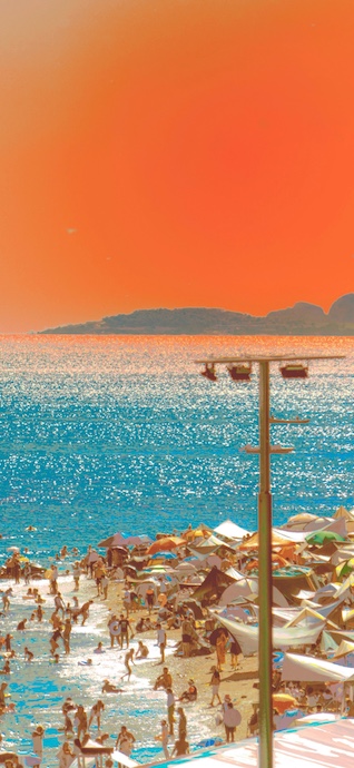 Ein belebter Strand im Sommer mit türkisfarbenem Wasser und einem leuchtend orangefarbenen Himmel.