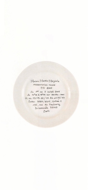 A white ceramic plate with handwritten black French text by Maison Martin Margiela on a clean white background.
