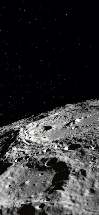 Vue verticale en noir et blanc de la surface de la lune avec ses cratères et un ciel étoilé.