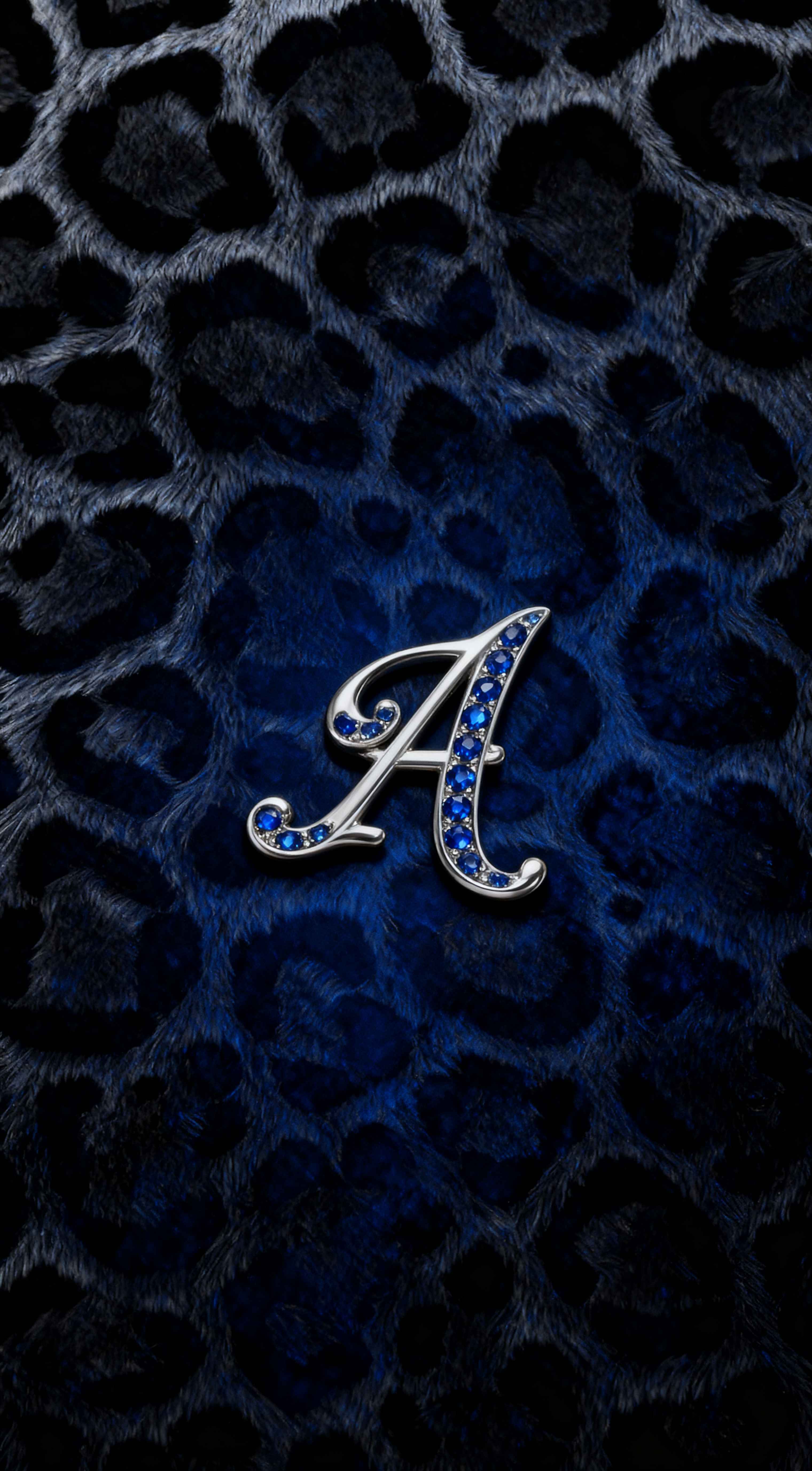 Silver jeweled letter A initial on a royal blue and black leopard print faux fur texture background.