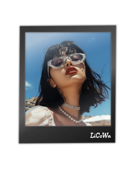 A minimalist black polaroid-style photo frame containing a single photo of a stylish woman with sunglasses and jewelry against a blue sky.