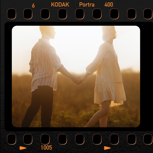 Ein Vintage-Filmstreifen-Rahmen mit der Aufschrift 'KODAK Portra 400', der ein Paar beim Händchenhalten zur goldenen Stunde zeigt.