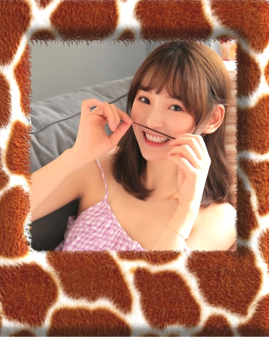 Photo d'une jeune femme souriante entourée d'un large cadre en peluche au motif tacheté de girafe marron et blanc.