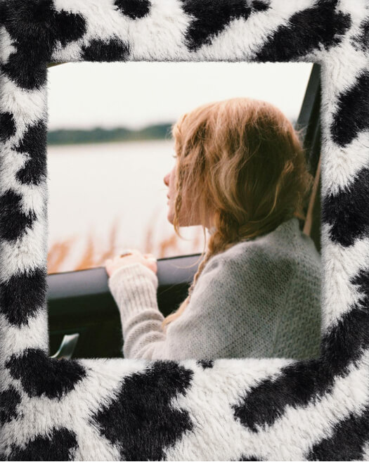 A single photo frame with a black and white cow-print furry texture surrounding an image of a girl looking out a car window.