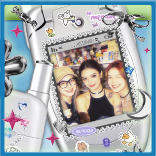 Un cadre photo téléphone à clapet argenté Y2K avec une photo de trois amies, décoré de strass et d'autocollants colorés.