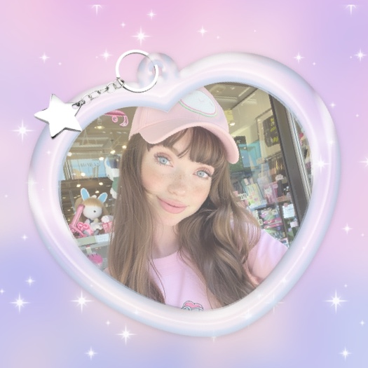 Un marco de foto en forma de llavero de corazón blanco con un dije de estrella plateada sobre un fondo degradado pastel con brillos.