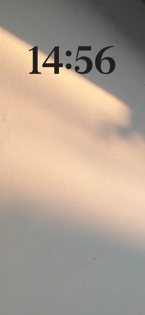 A minimalist wall with natural sunlight and shadow patterns, serving as a customizable live wallpaper template.